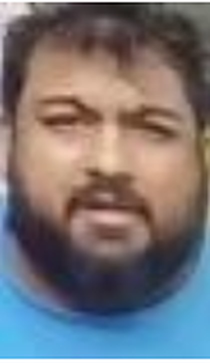 Low-resolution doorbell-camera capture of Joseph Tennis looking up at the camera: dark hair, full beard, blue T-shirt.